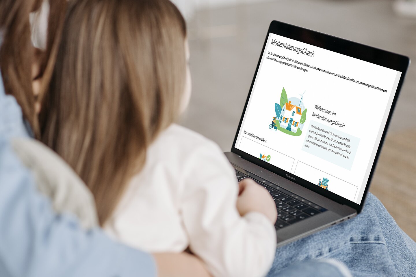 Mutter und Kind durchlaufen den ModernisierungsCheck an ihrem Laptop